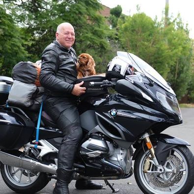 PAWS volunteer John Southwood on his motorbike, with a small dog riding on the back