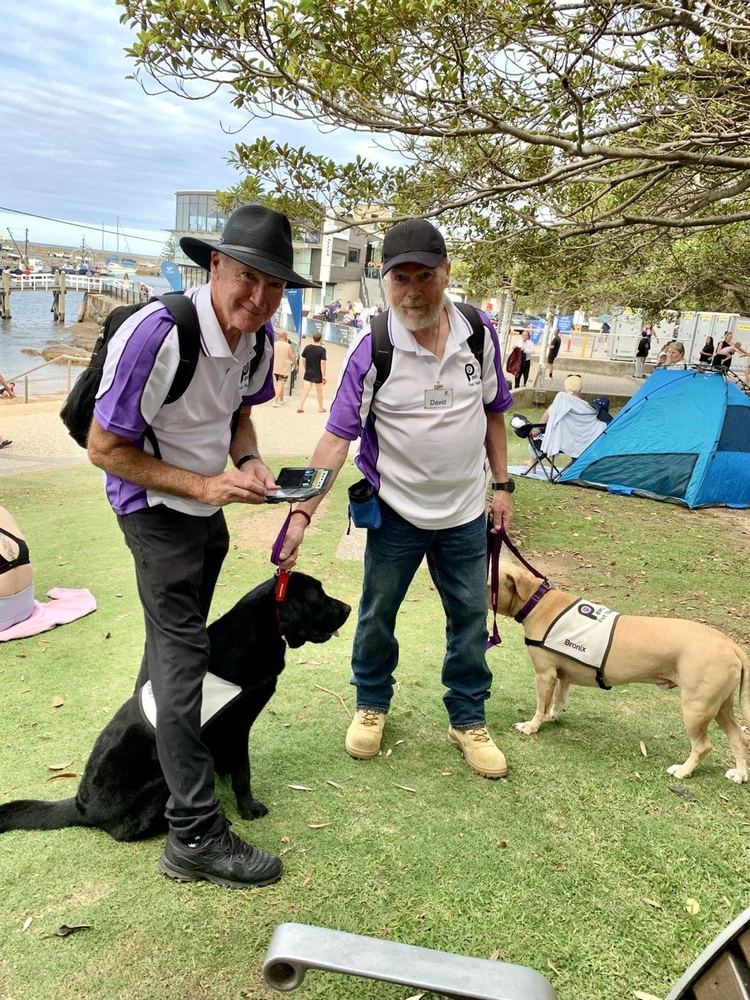 Two PAWS volunteers with their therapy dogs at a community outing